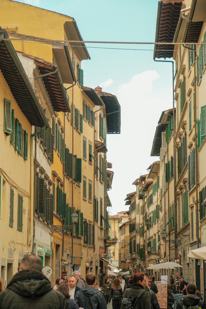 a group of people walking down a street next to tall buildings