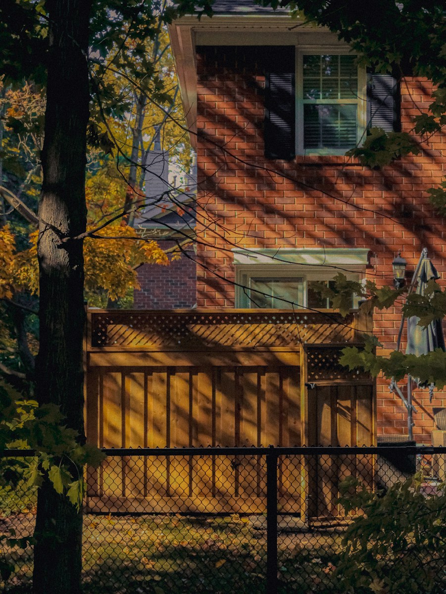 Brick house with wooden fence and autumn leaves