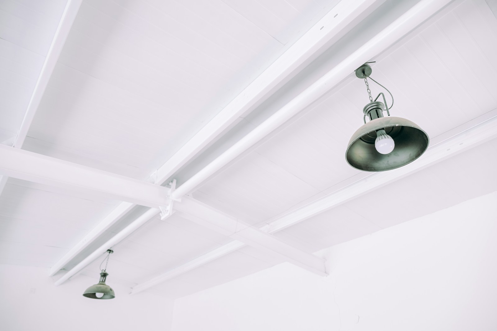 White ceiling with exposed beams and two industrial pendant lights