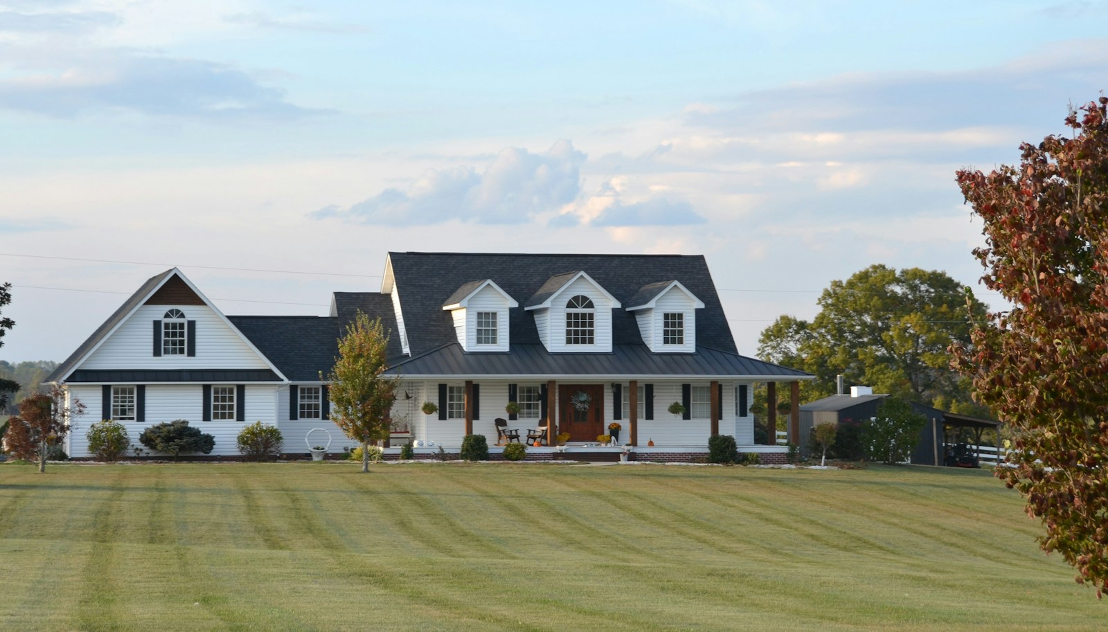 A large white farmhouse with a wrap-around porch