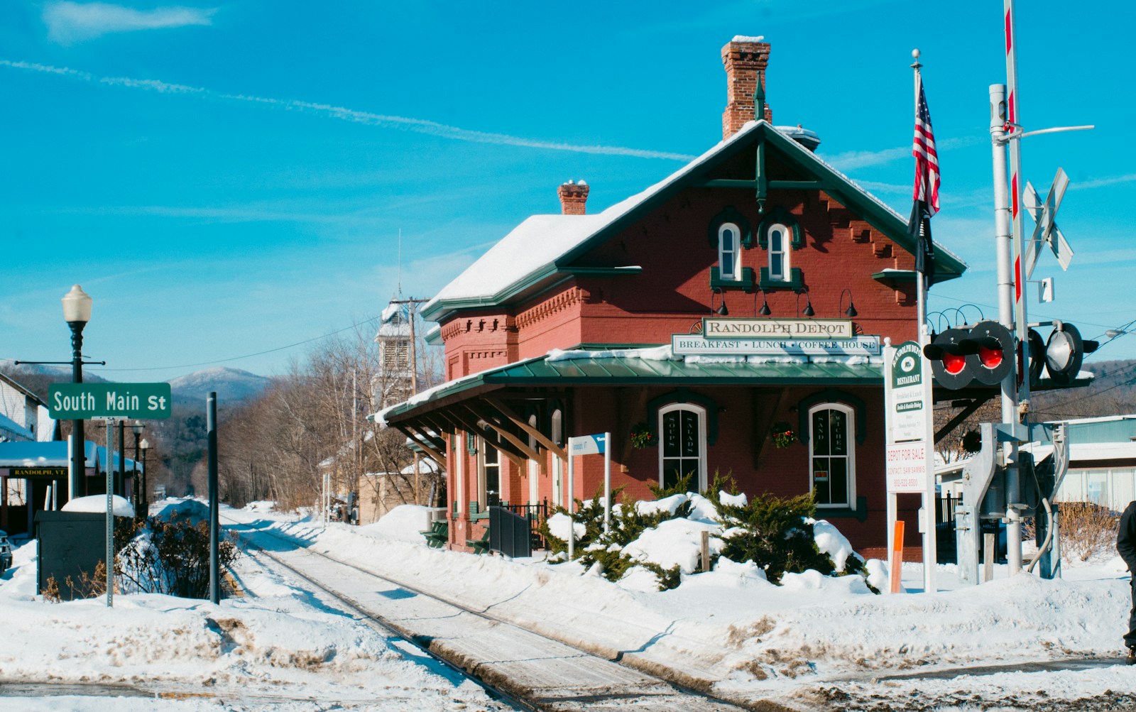 brown and white wooden house surrounded by snow covered field under blue sky during daytime
