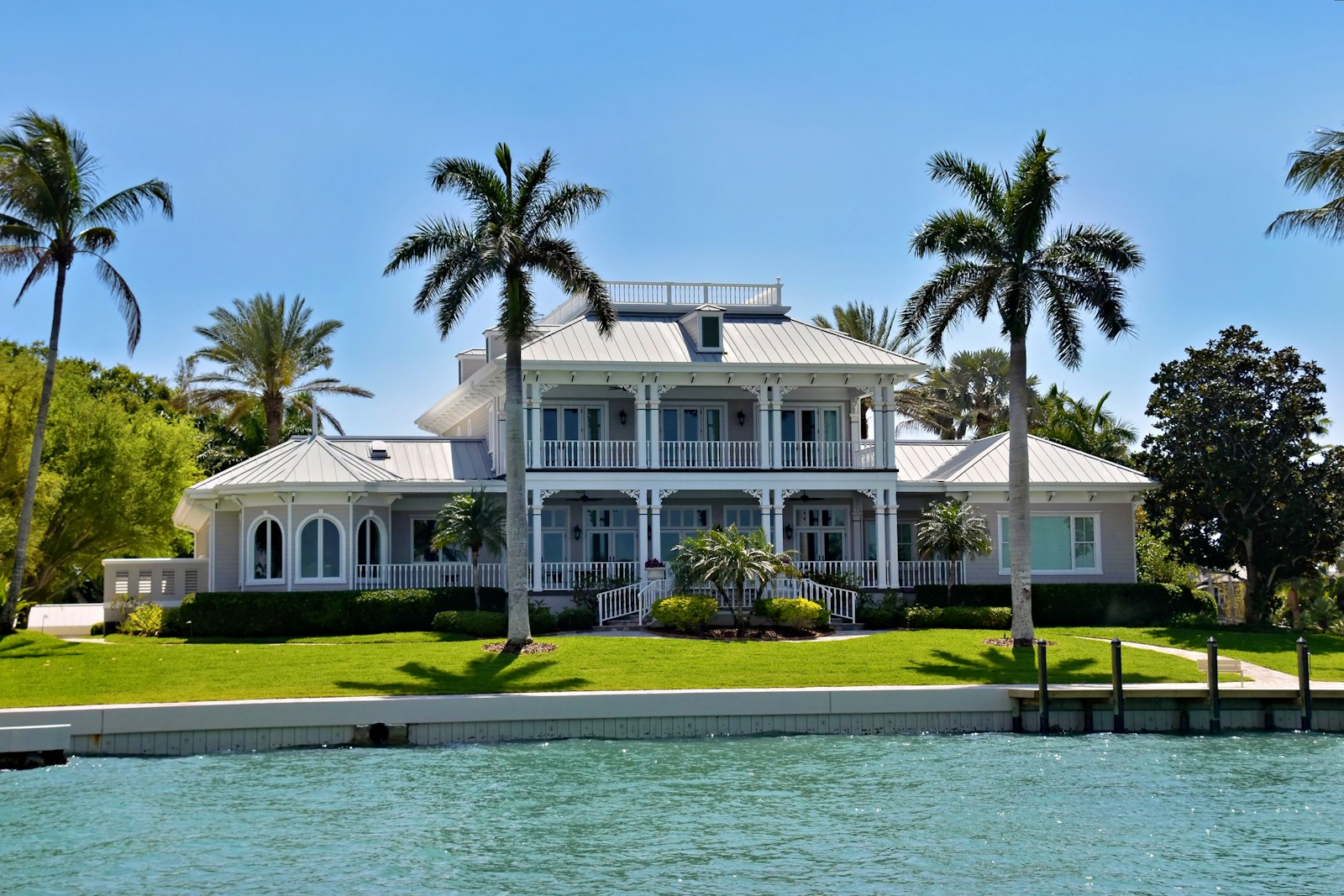 A large white house with palm trees by the water