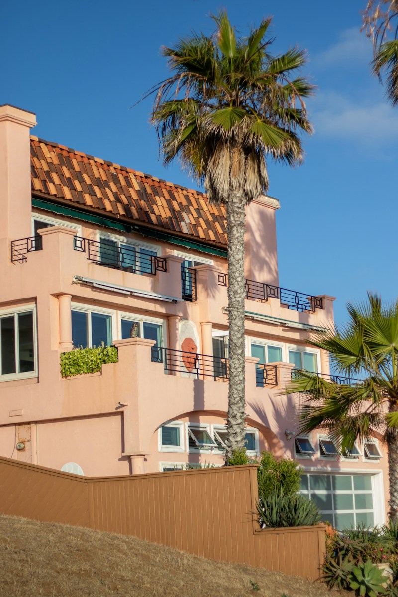 Pink building with palm trees against a clear blue sky