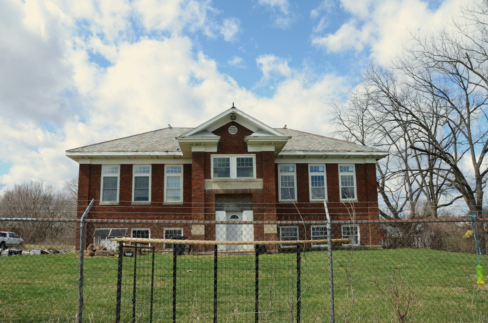 Old brick building behind a chain-link fence