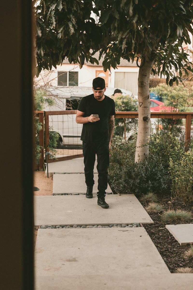 man in black t-shirt and black pants standing on gray concrete floor during daytime