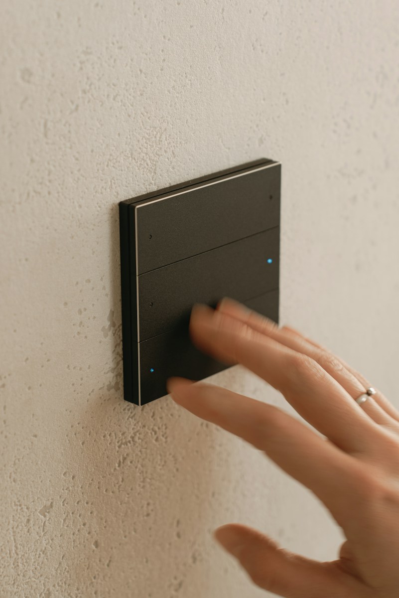 A person's hand touching a button on a wall