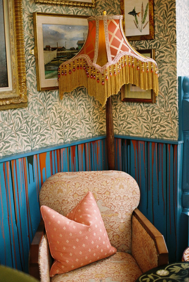 Ornate lampshade above a patterned armchair with pillow