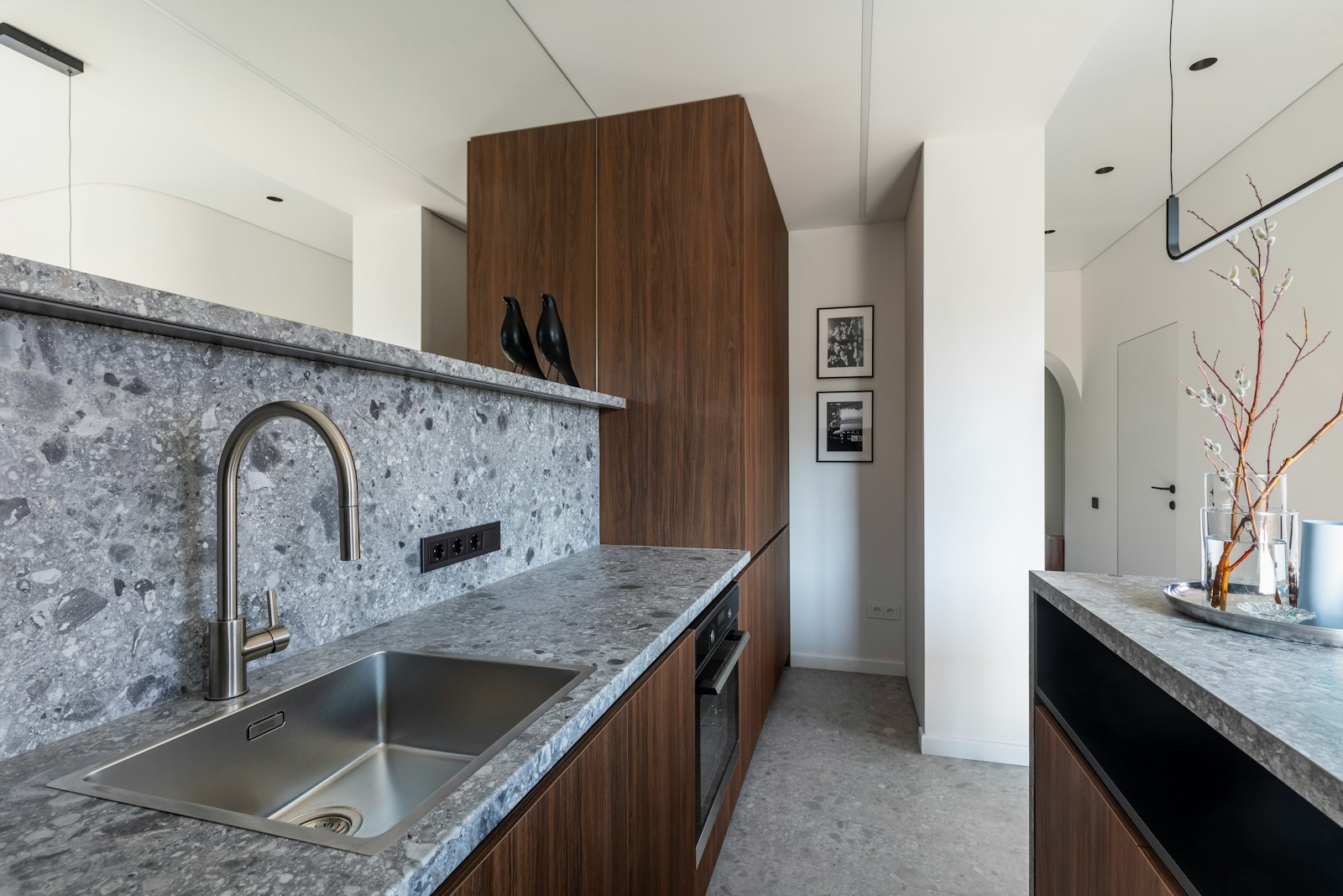 Modern kitchen with gray speckled countertops, wooden cabinets, and sink