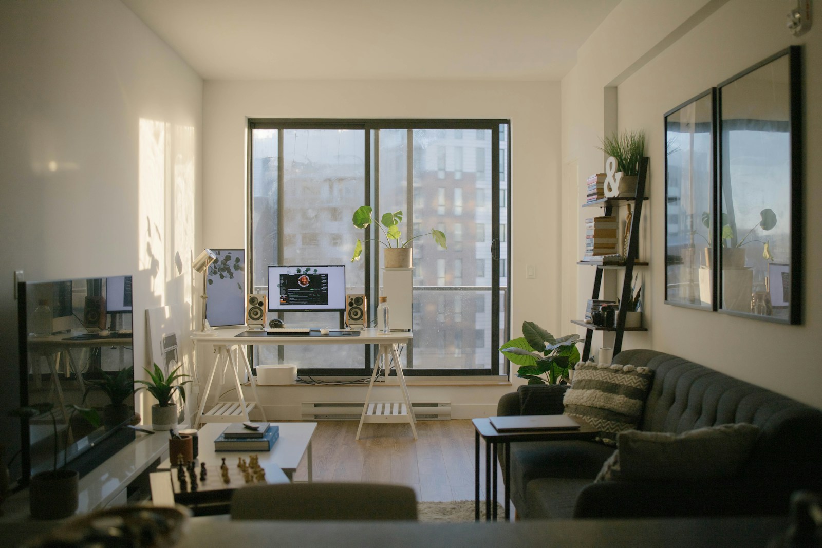 A sunlit home office with a desk, computer, and sofa in a living room