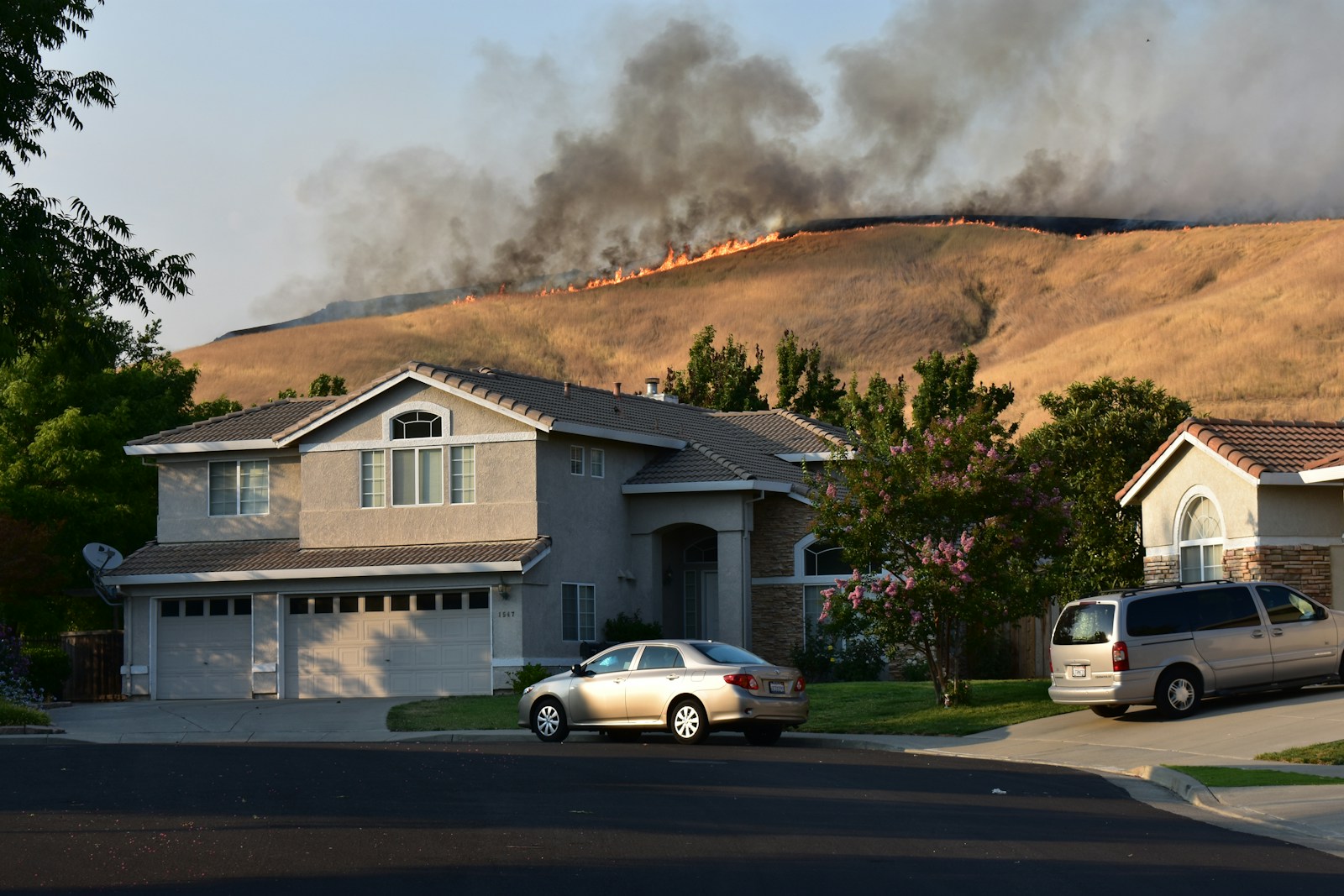 Wildfire burns a dry hillside near suburban homes