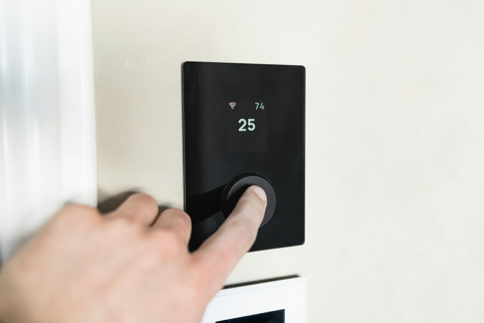 Finger pressing button on digital thermostat display