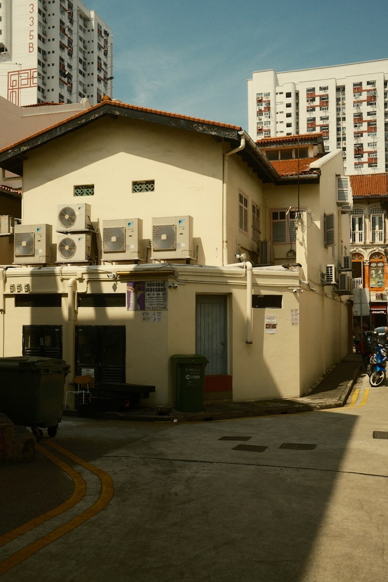 A cream-colored building with air conditioning units in a narrow urban alleyway