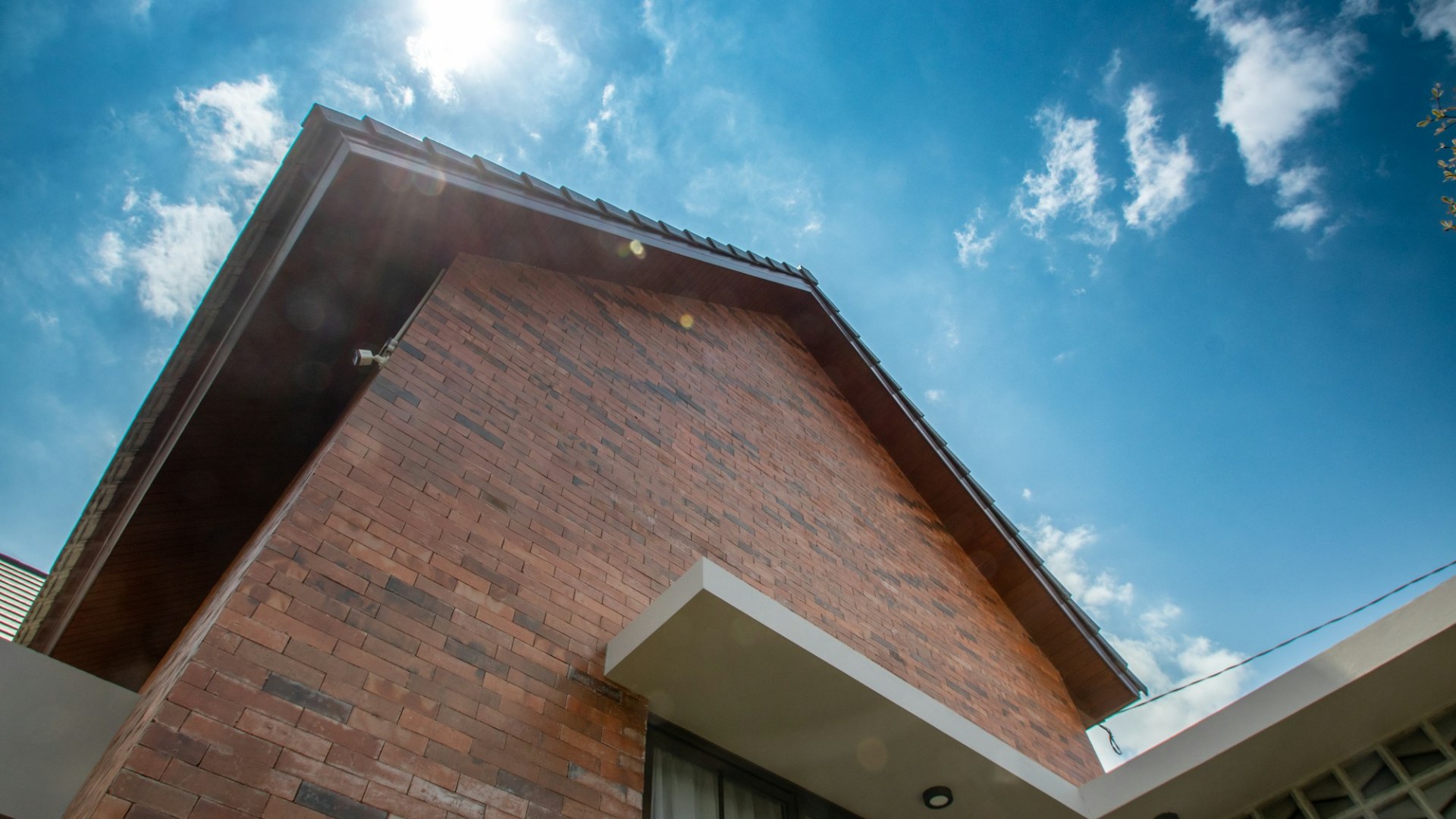 A brick house exterior against a blue sky. Photo by Yudiono Putranto on Unsplash.