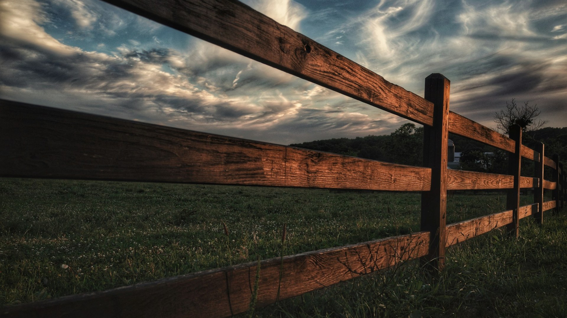 A brown wooden fence beside a green grass field. Photo by Edan Cohen on Unsplash.