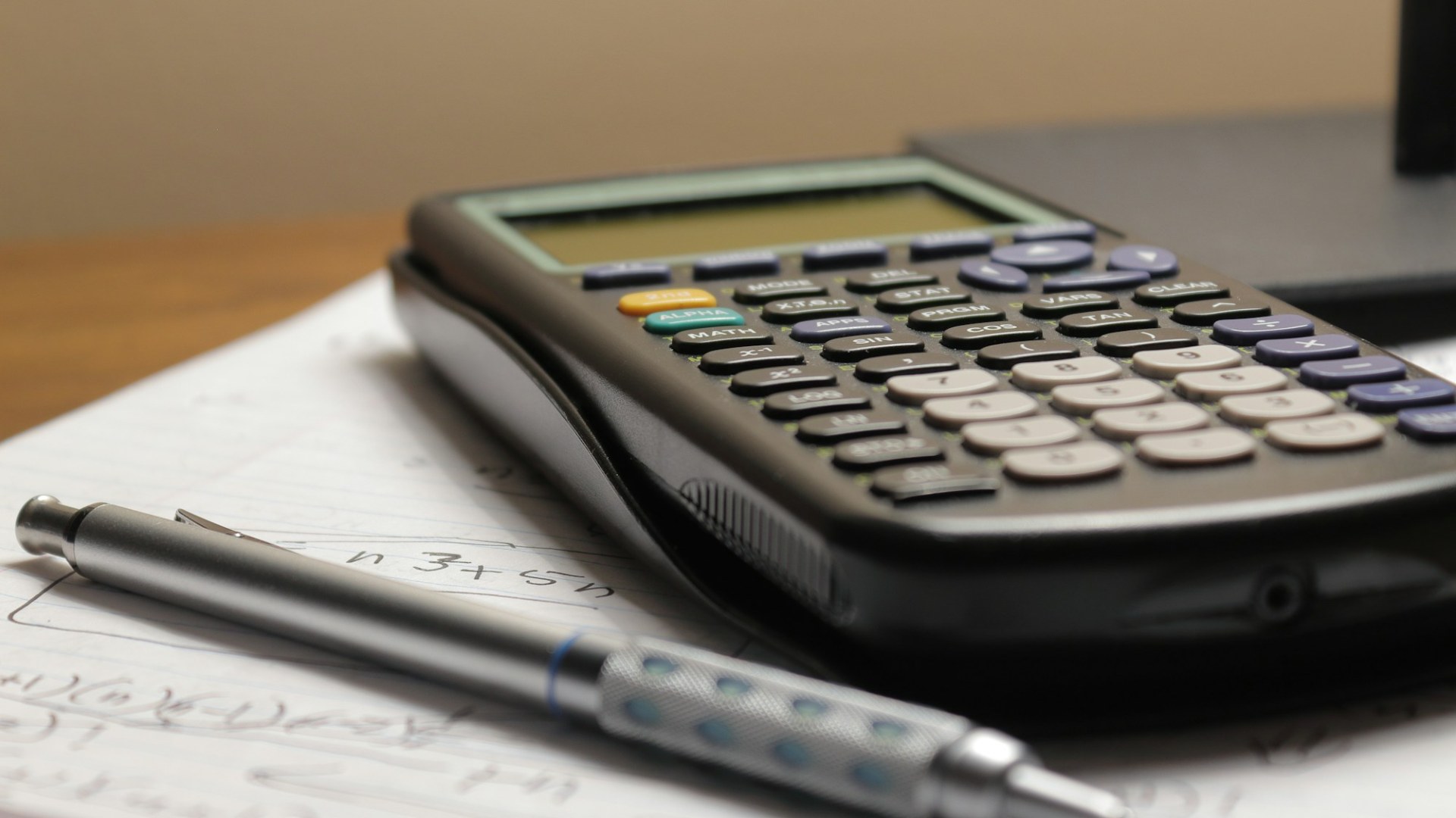 A calculator and a pen on a sheet of paper. Photo by Aaron Lefler on Unsplash.
