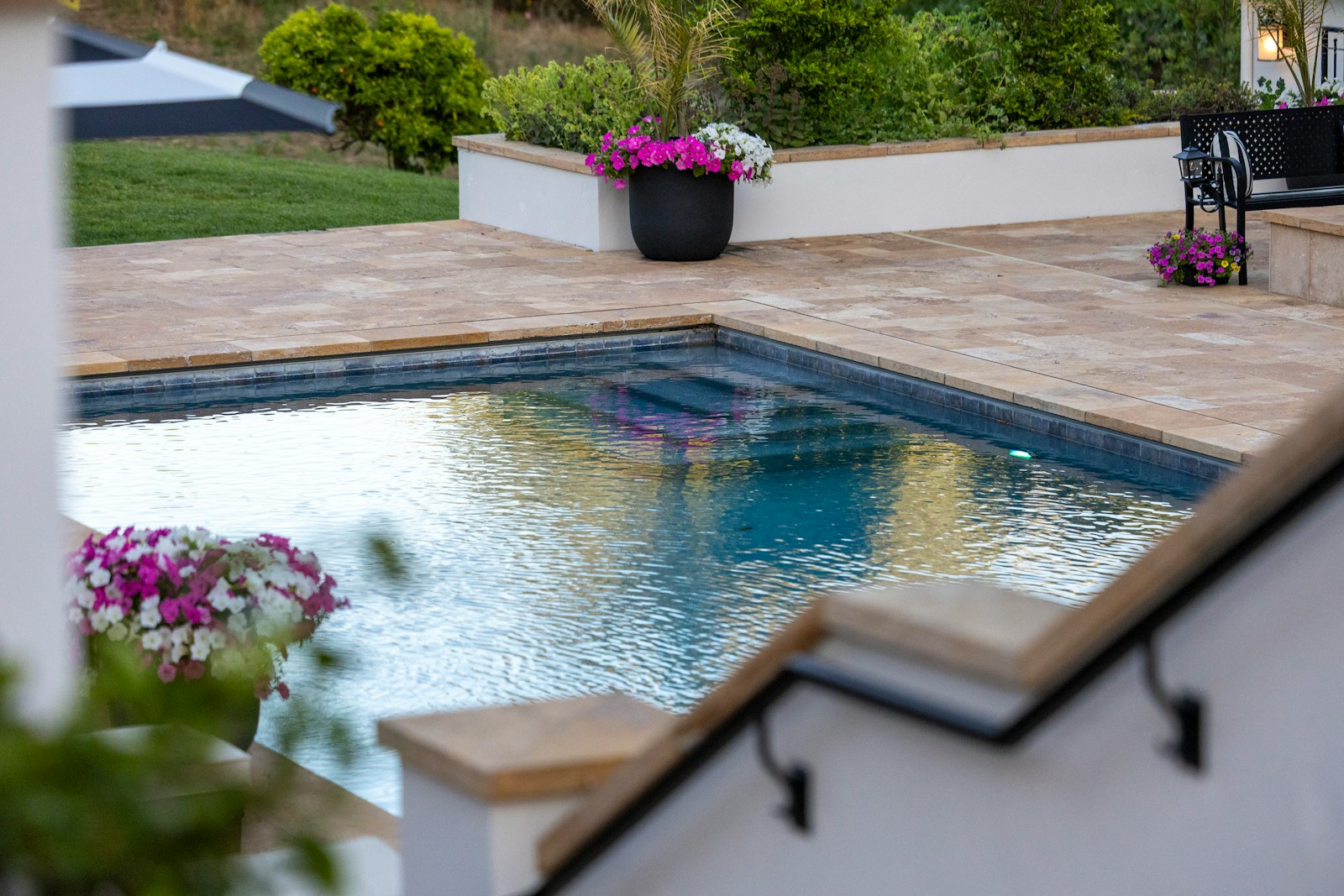 Outdoor swimming pool with surrounding patio and vibrant flowers